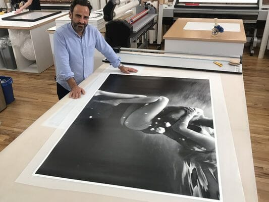 man standing over large photo print