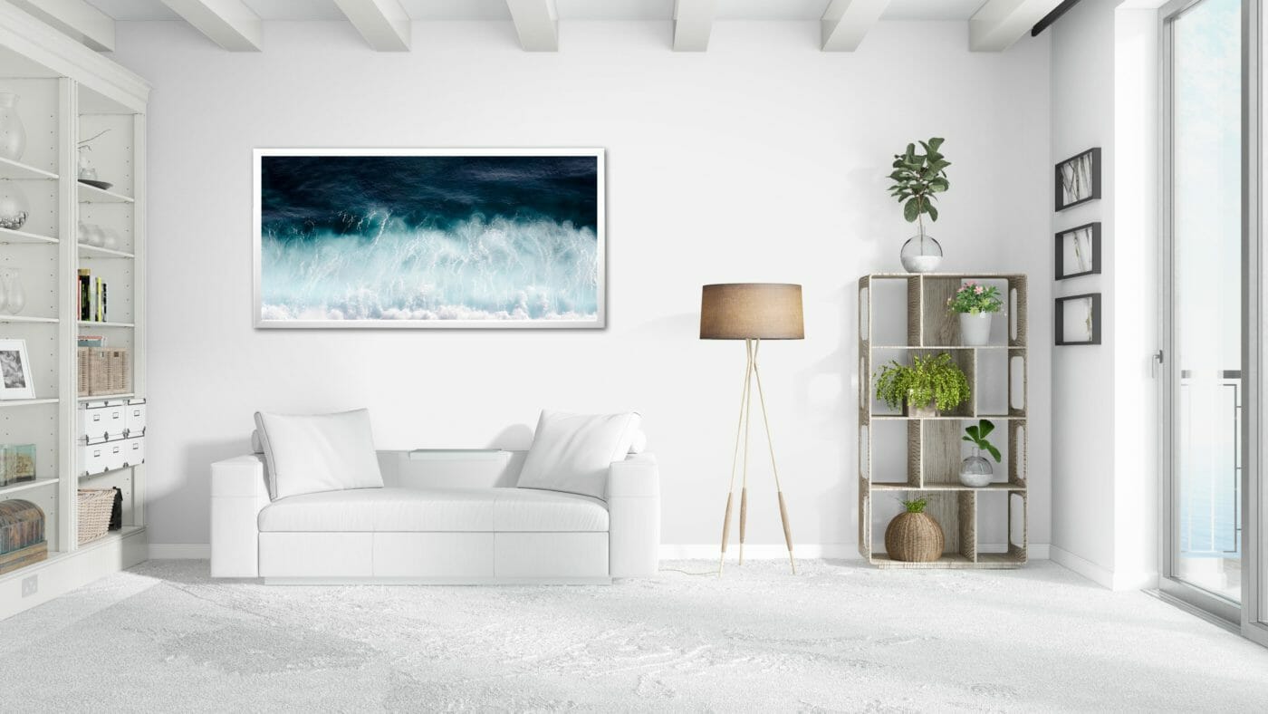 white couch with a framed picture of the ocean above it