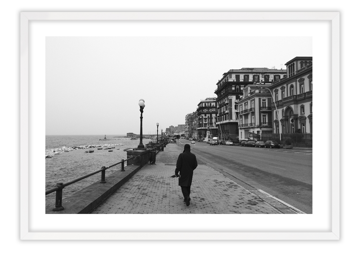 black and white photo of man walking down street